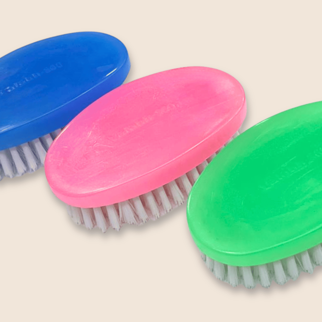 Three colorful brushes with blue, pink, and green handles on a beige background.